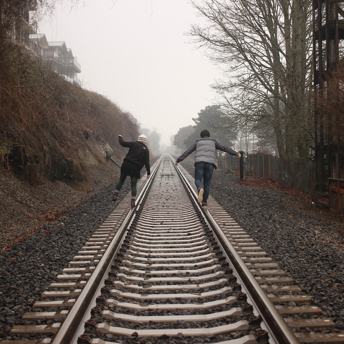 two person walking on the train rail